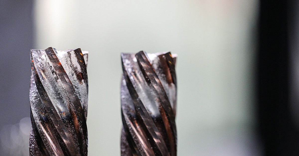Close-up of built-up edge and flute wear on two carbide end mills before reconditioning.