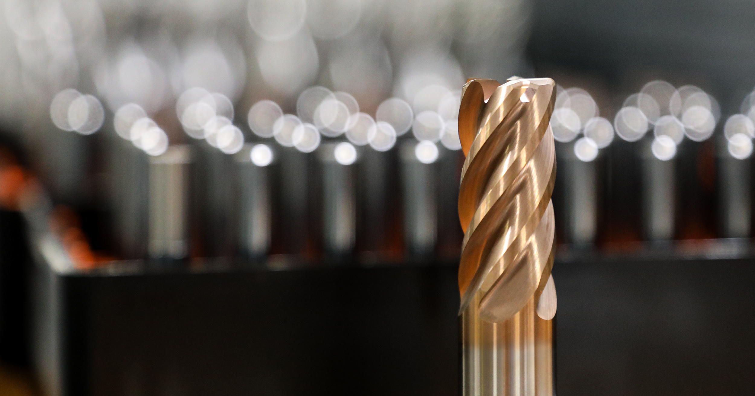 Hero headshot image showing a TiAlSiN-coated end mill with a group of end mills behind. The end mill in focus is coated with TiAlSiN, which leaves the tool with a bronzed finish from the tools tip to the beginning of its shank.