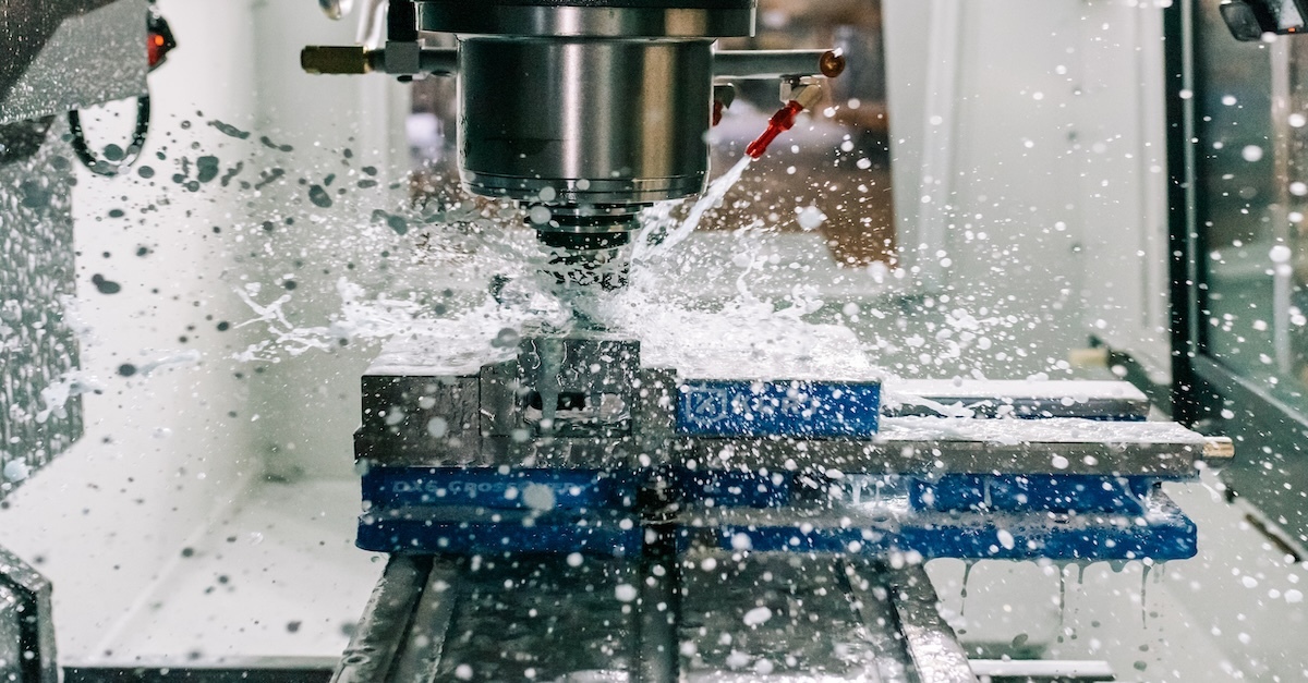 Wet Machining with Flood Coolant CNC mill spindle cutting a workpiece clamped in a vise, with coolant flooding the cut zone during machining